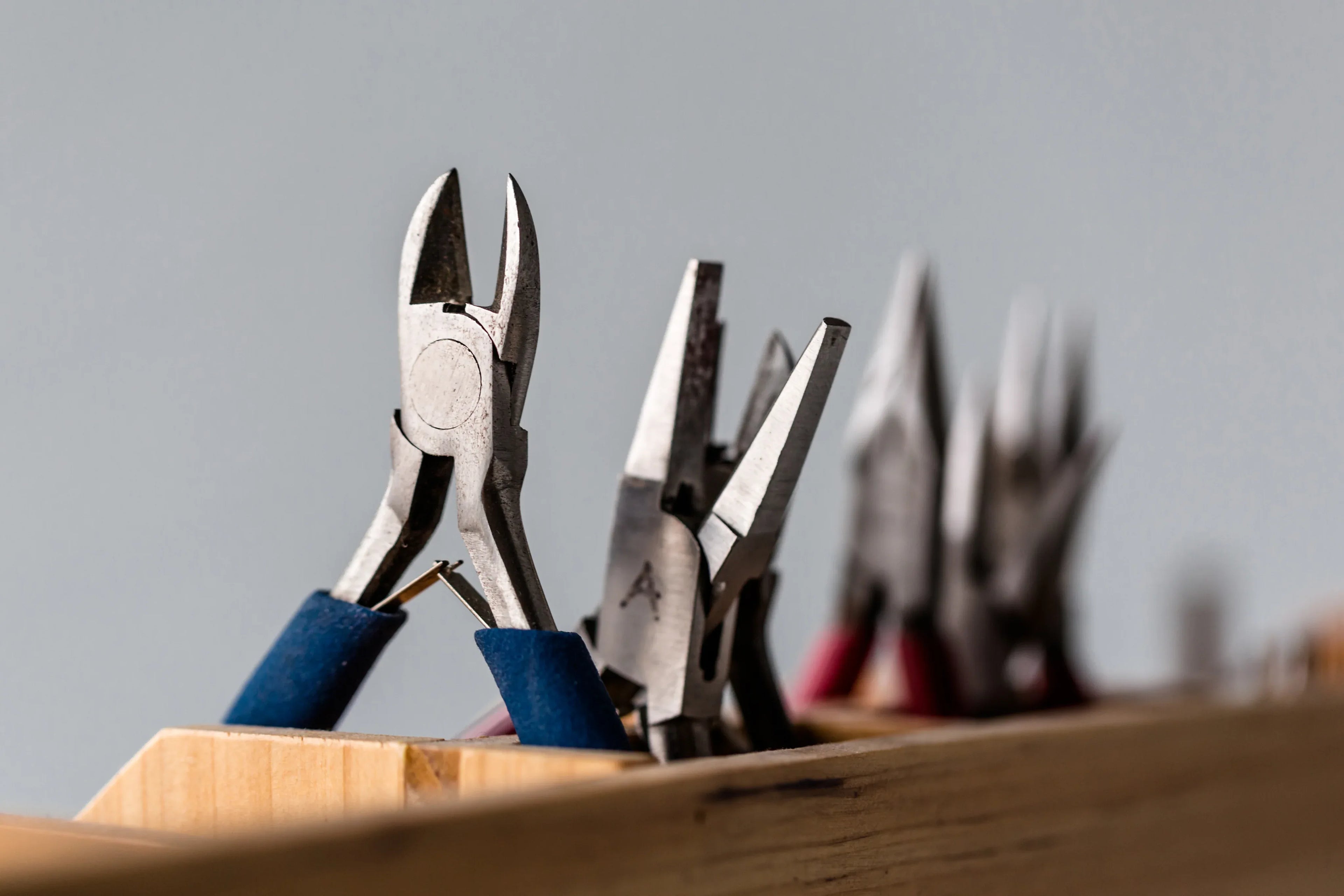 Set of pliers on a wooden block with a grey background